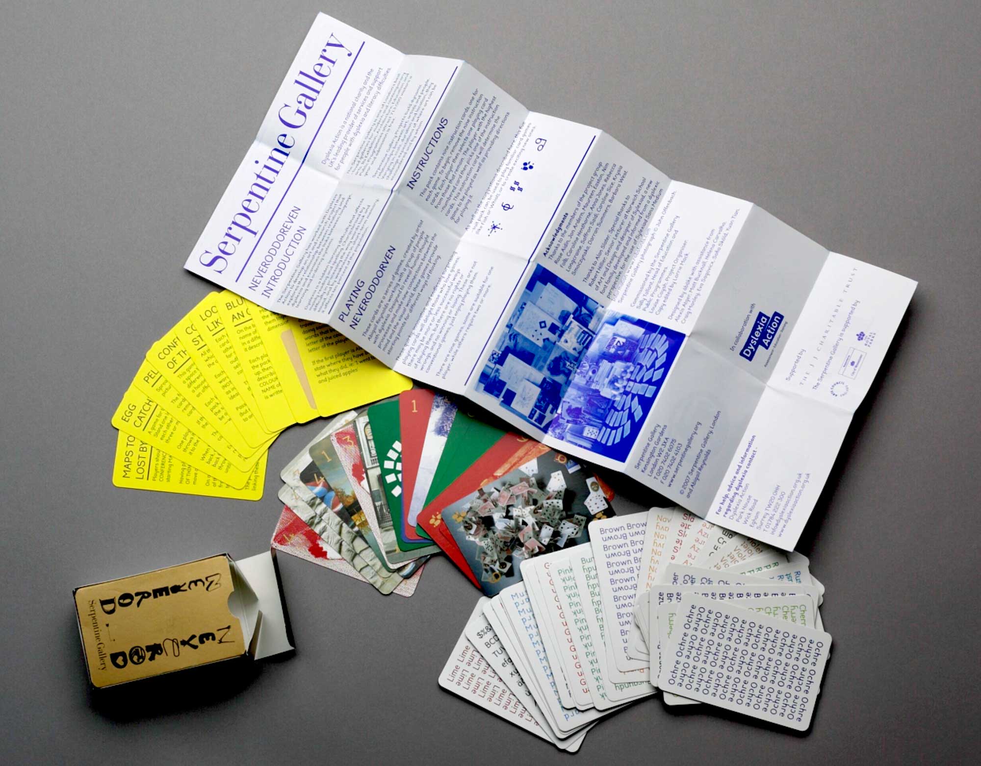 Photo of a flyer in bright blue from the Serpentine Gallery, and cards in yellow and white. Photo shot from above